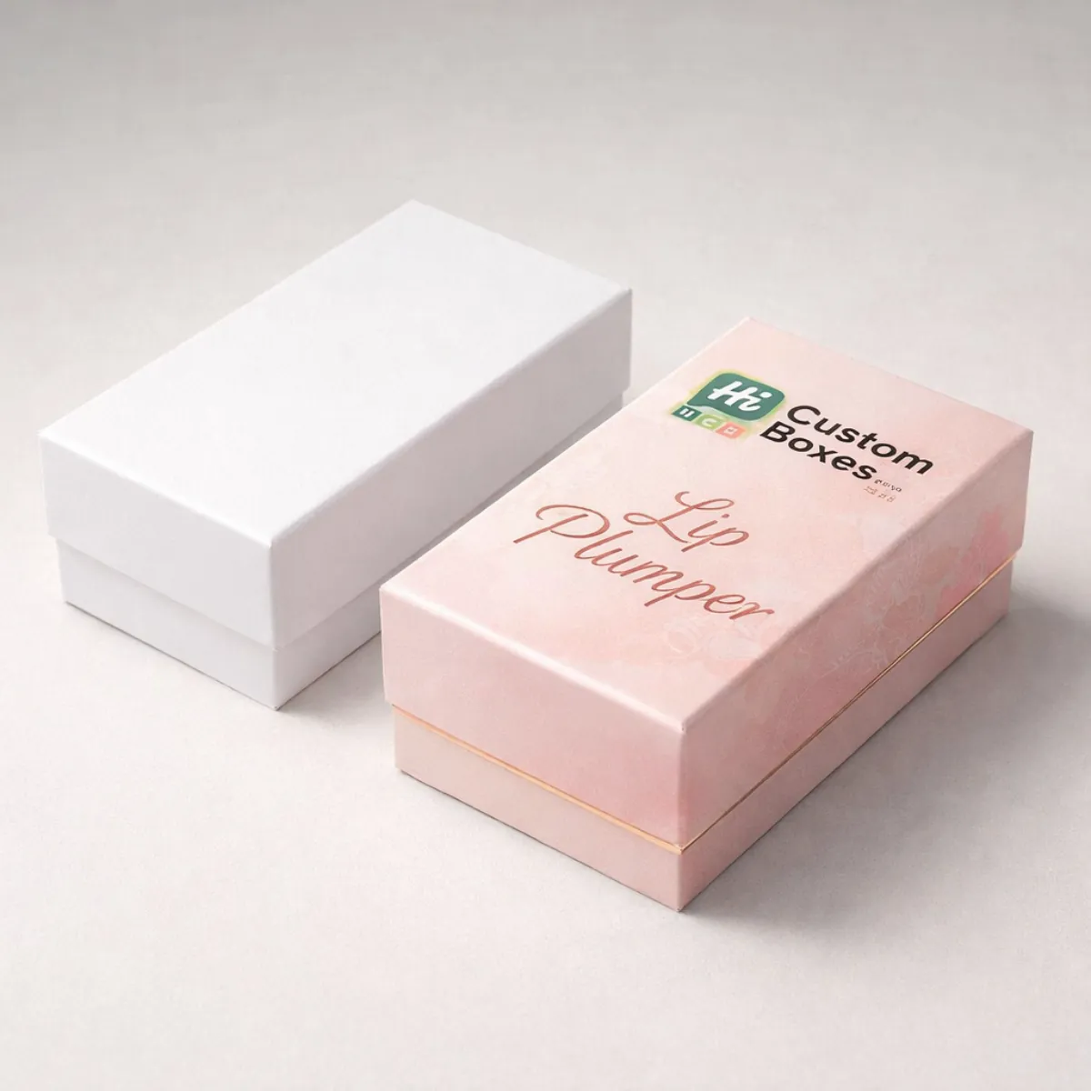 Two sturdy rectangular boxes for lip plumpers, one plain white and one pink with floral patterns. class=